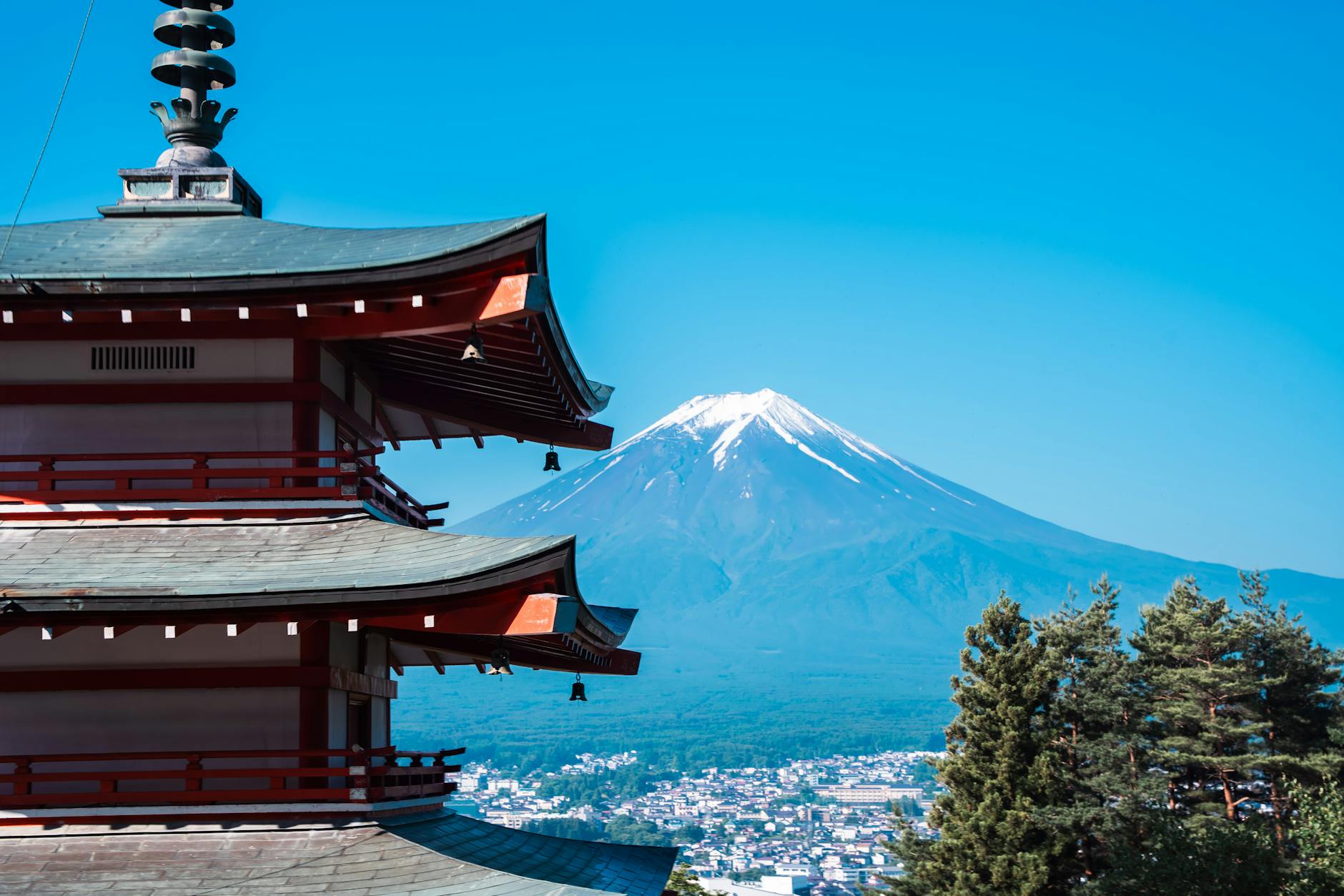 View of a traditional pagoda with a landscape of Mount Fuji in the background against a clear blue sky.