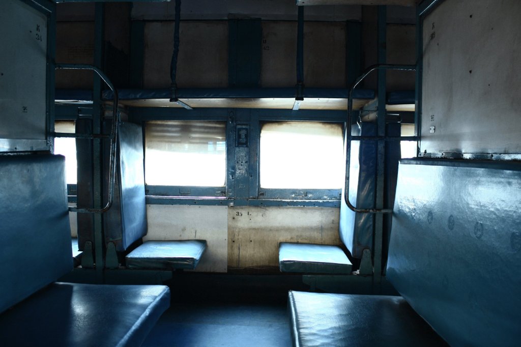 Interior of a train compartment featuring empty seats and large windows.
